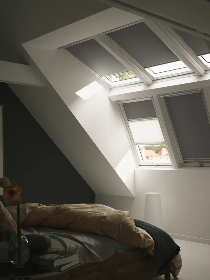 Store DUO VELUX occultant et tamisant sur plusieurs fenêtres de toit dans une chambre